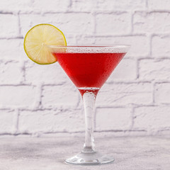 Glass of cosmopolitan cocktail decorated with lime
