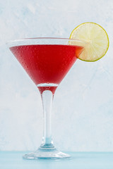 Glass of cosmopolitan cocktail decorated with lime