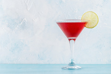 Glass of cosmopolitan cocktail decorated with lime
