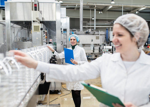 Female workers in bottling factory checking water bottles before shipment. Inspection quality control. 