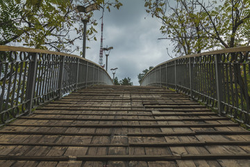 Wooden bridge on cloudy sky background