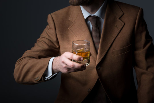 Handsome bearded businessman is drinking expensive whisky closeup. No face