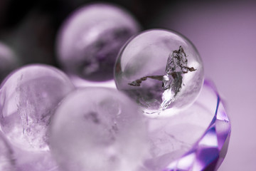 Macro shot of transparent crystal balls with colorful ornaments and sun reflections in it, on turquoise glass pad. Fortune telling. Love, money, luck, success