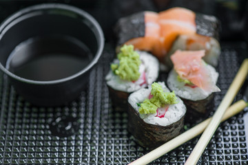 Fresh and delicious maki and nigiri sushi rolls with tiger shrimps, salmon, philadelphia cheese and wasabi served with soy sauce and ginger slices on black take away plate. Japanese food in restaurant