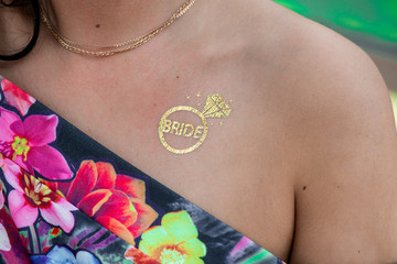 Macro shot of temporary tattoo of ring. Cheerful bride and bridesmaids party before wedding. Women...