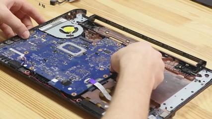 Laptop disassembling in repair shop, close-up. Disassembled computer motherboard on repairman workplace. Electronic development, technology fixing concept
