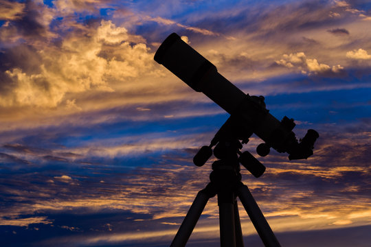 Silhouette of a telescope with evening sky in the background.