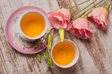 Tea in  chines cups  and a pink flowers on wooden background