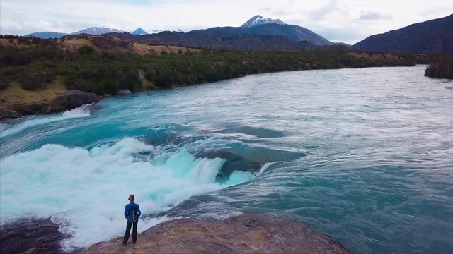 Hiker stands on the coast of powerful river. Aerial view of the rapids of river of Baker. Patagonia, Chile