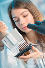student woman with multi pipette and other PCR items in microbiological / genetic laboratory