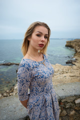 Young hot sexy woman in a short  dress walking near the sea