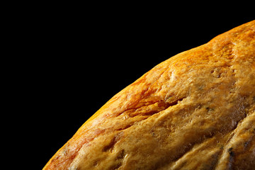 part of the surface of a dried Spanish ham jamon on a black background. background a food of yellow color with a place for an inscription. texture surface of oily pig's foot macro shot
