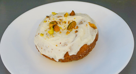 A Pistachio Covered Cream Cheese Iced Cake Doughnut on a white plate