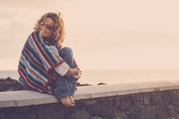 Fototapeta na wymiar beautiful woman sit down with a mesican poncho near the ocean