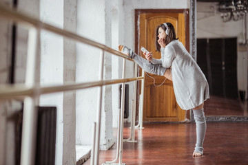 Young ballerina with headphones on training in studio