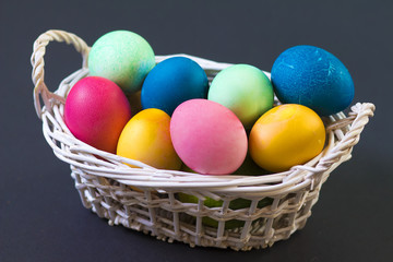 Easter multicolored eggs in basket on black background. Easter theme. Conceptual background for the spring religious holiday of Easter.