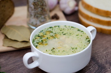 Mushroom soup with croutons in a white dish is on a wooden table.