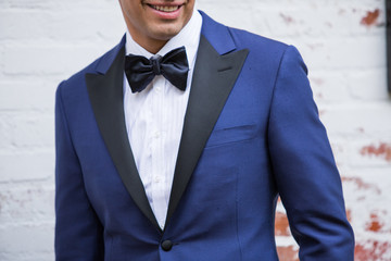 Closeup of a Smiling Man wearing a Black and Blue Suit and Bow Tie