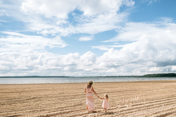 Mom and daughter are walking along the beach