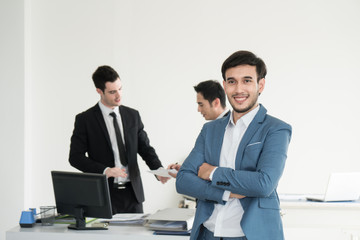 Portrait of business man holding tablet and feeling failed, sad, distraught, frustrated while team mates discussing in the background