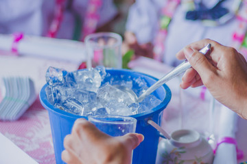 Close-up th hands add ice to the glass to distribute to friends at the table on party of Graduation.