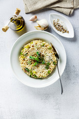 Italian risotto with spring fresh asparagus and parmesan cheese in a plate and ingredients on a stone white table