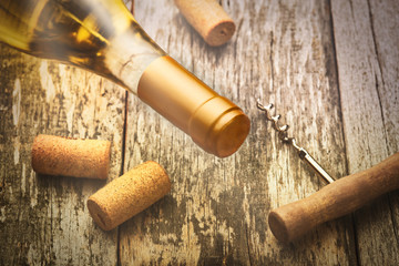 Fototapeta na wymiar Glass bottle of wine with corkscrew on wooden table background