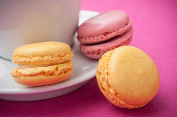 Obraz na płótnie Canvas assortment of french macarons pastry and cupof coffeee on pink background