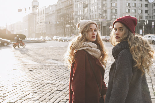 Portrait of sisters standing on city street during winter