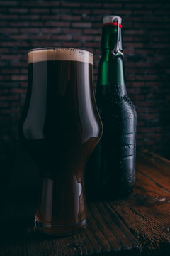 Stout beer in glass abd bottle on dark background