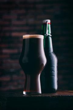 Stout beer in glass abd bottle on dark background