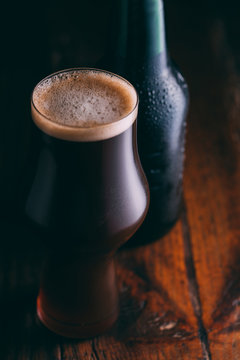 Stout beer in glass abd bottle on dark background