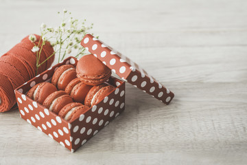 Stylish red dots box with tasty macarons on wooden background. Minimalist concept of style and french chic, copy space and selective focus.