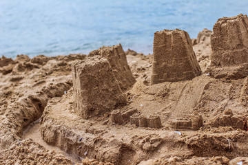A sandcastle on a sandy beach, set against a bright blue sea water