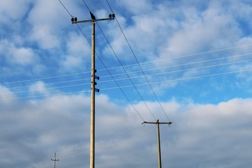 Strommast aus Holz, blauer Himmel mit Wolken