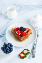 Traditional Ukrainian or Russian pancakes with fresh berries and sauce on the table