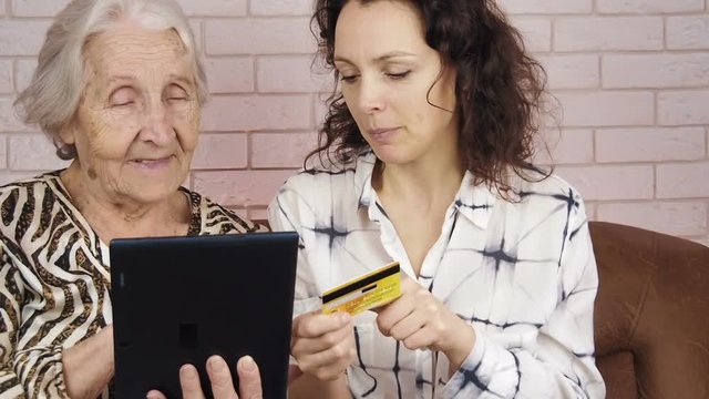 Payment by credit card. Young woman is teaching an elderly woman to use a credit card.