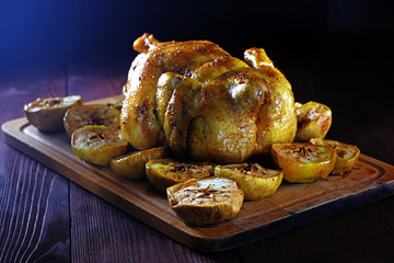 Juicy baked chicken with apples on dark wooden background in rustic style