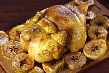 Juicy baked chicken with apples on cutting board