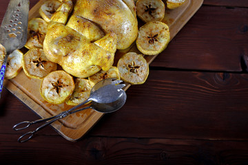 Juicy baked chicken with apples on cutting board