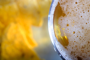 A glass of light amber beer, nachos in a glass cup, close-up