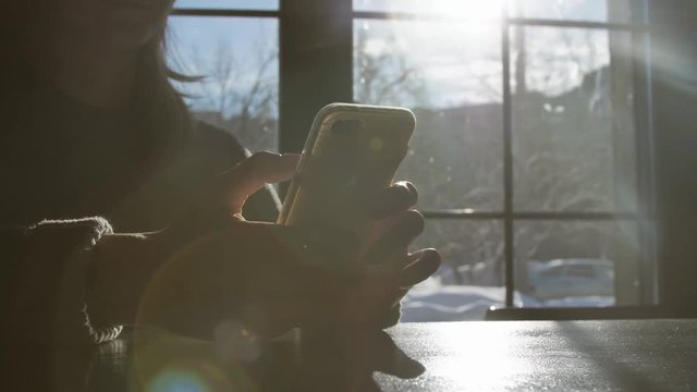 Woman typing message on touch phone in sunshine. Using mobile. Sunny moning.