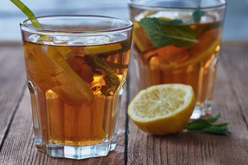 Ice tea with lemon and mint in a glass on a woodenbackground