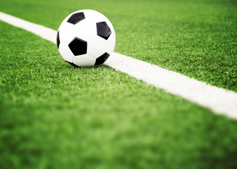 Naklejka na ściany i meble Traditional soccer ball on grass field 
