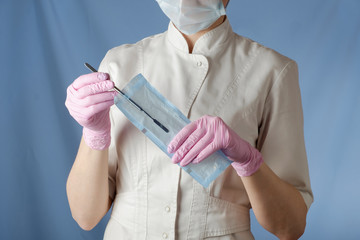 Dentist prints disinfected tools from a special package, on a blue background