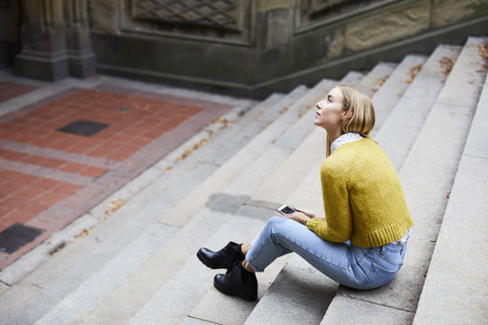 Thoughtful young woman sitting on stairs 