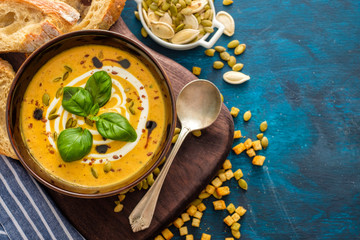 Delicious homemade pumpkin soup with basil leaves. Top view.