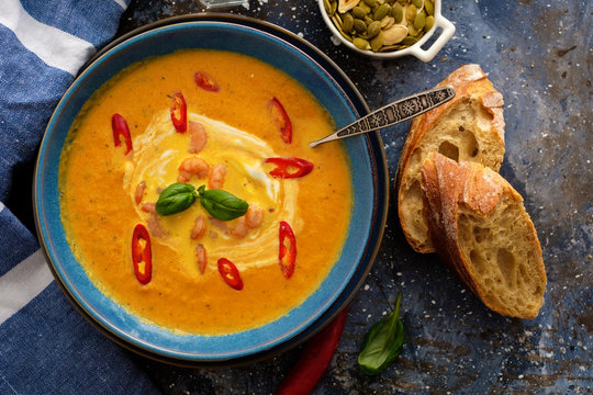 Delicious homemade pumpkin soup with prawns, chili and basil leaves.