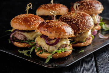 Homemade juicy burgers with beef, cheese and caramelized onions on the wooden table. Street food, fast food © FoodAndPhoto