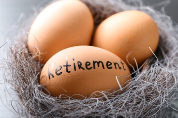 Egg with word RETIREMENT in nest, closeup. Pension planning